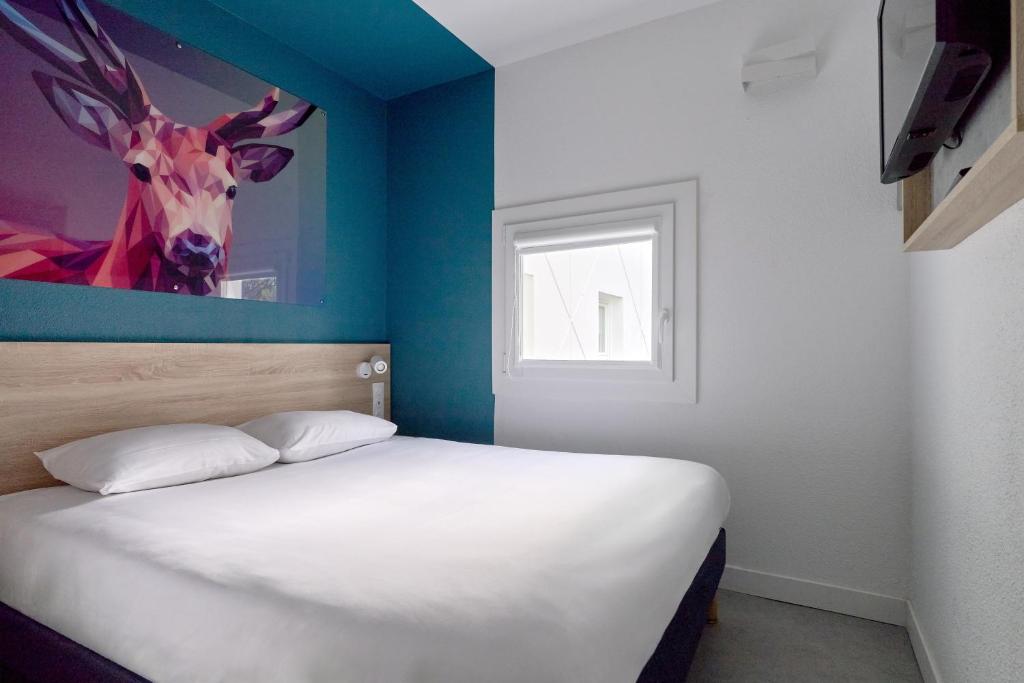 a bedroom with a bed with a painting of a deer on the wall at Kyriad Direct Nevers Nord - Varennes Vauzelles in Varennes Vauzelles