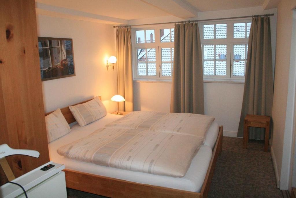 a bedroom with a large bed and two windows at Fachwerkferienhaus Helmbrecht in Goslar