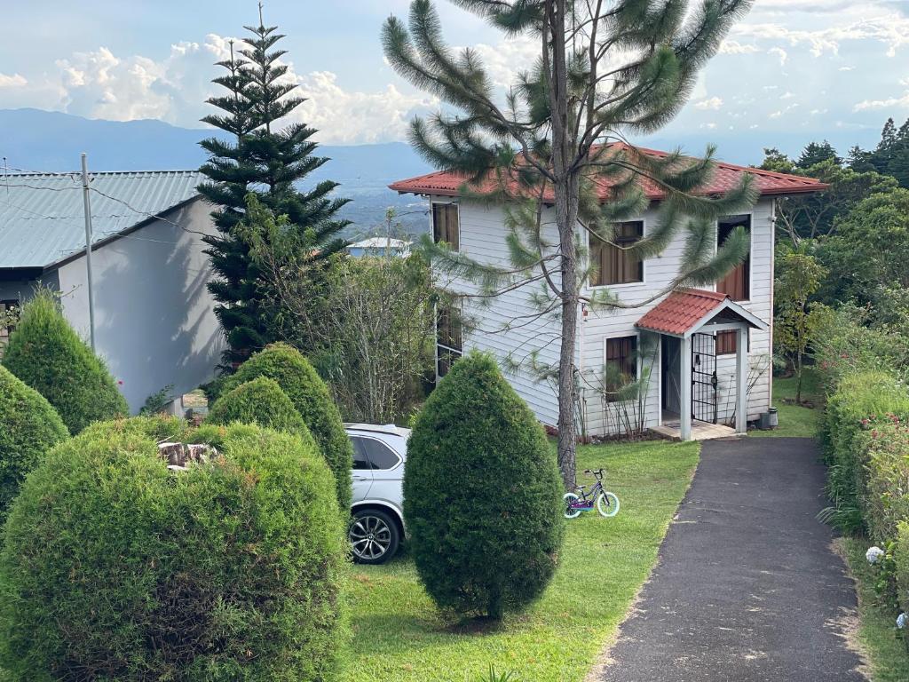 une voiture blanche garée devant une maison dans l'établissement Parque Nacional Volcán Poás Cabaña Abby, à Bajos Tigre