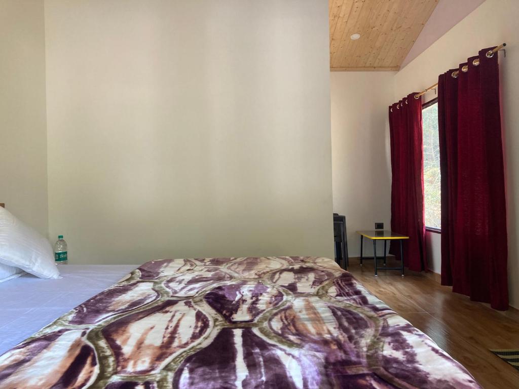 a bedroom with a bed with a blanket on it at Sattal Valley Resort in Bhīm Tāl