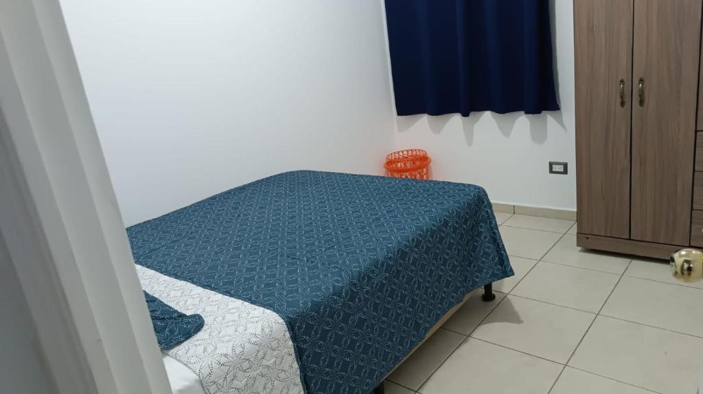 Una habitación con una cama con una manta azul. en ParadaHome en San Ramón