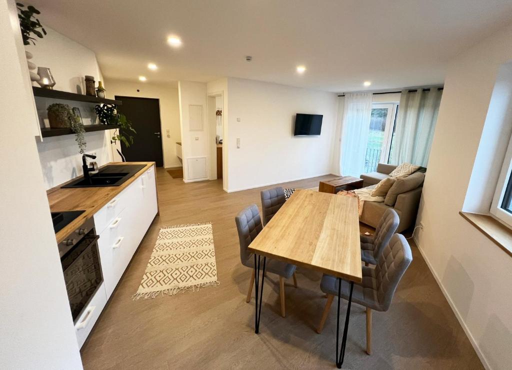 eine Küche und ein Wohnzimmer mit einem Holztisch und Stühlen in der Unterkunft FeWo Anders - Neubau mit Balkon im Bergischen Land in Reichshof 
