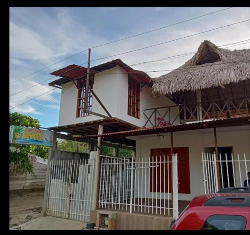 una pequeña casa blanca con techo de paja en Cabaña hospedaje las Gaviotas, en Moñitos