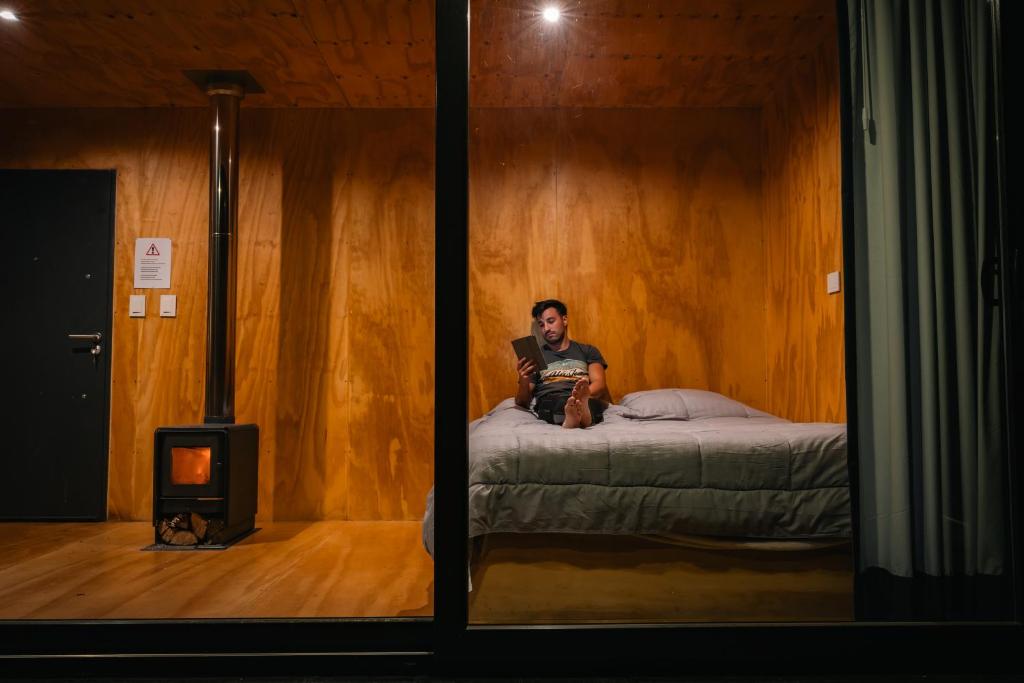 un hombre sentado en una cama en una habitación en El Bosque en San Carlos de Bariloche