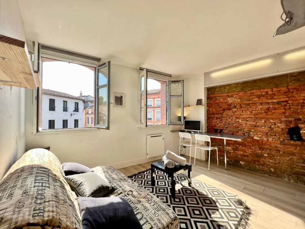 un salon avec un canapé et un mur de briques dans l'établissement Studio climatisé hyper-centre - 300m Basilique Saint Sernin, à Toulouse
