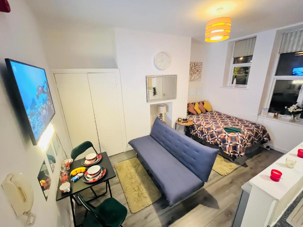 een woonkamer met een blauwe bank en een bed bij Studio flat in Shipley Central in Shipley