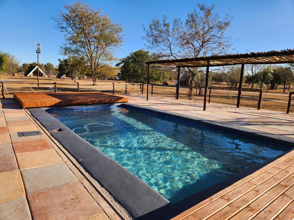 uma piscina com um deque e um pavilhão em Mzimkhulu Ranch & Resort em Dinokeng Game Reserve