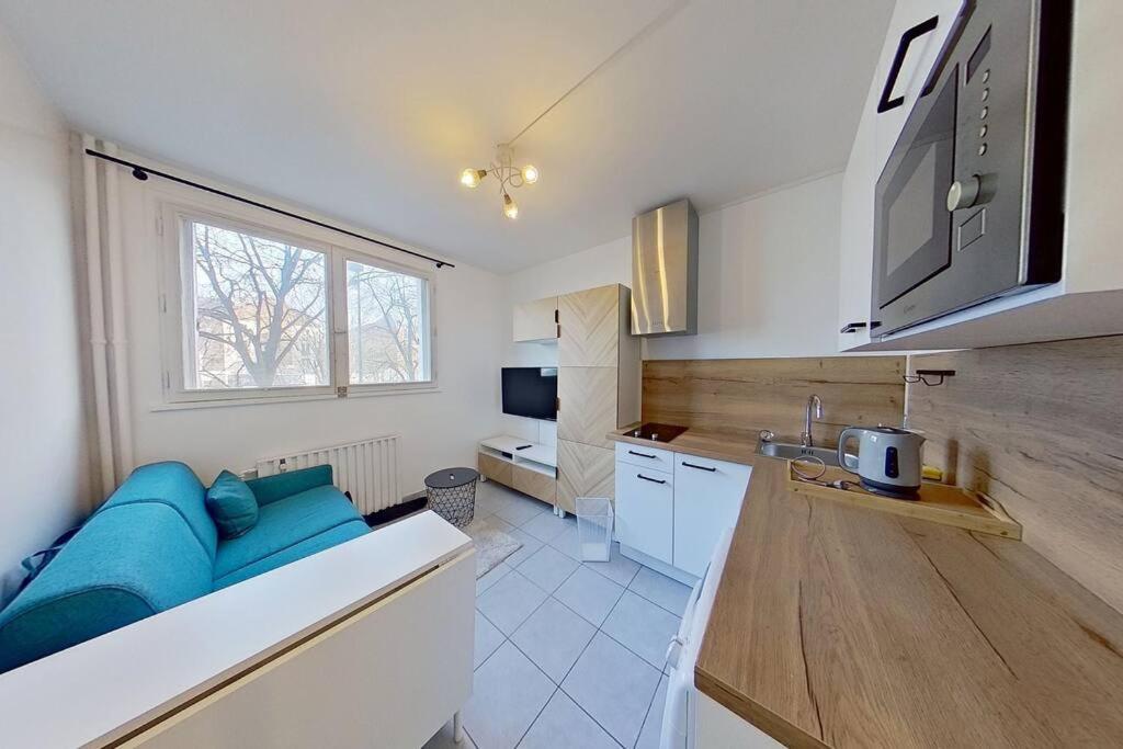 - une cuisine avec un canapé bleu dans une chambre dans l'établissement Studio Cosy proche Gare de Poissy RER A, à Poissy