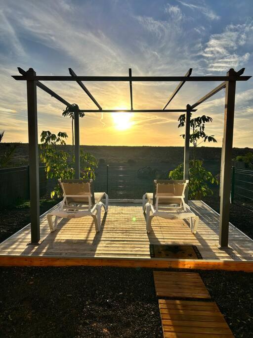 two chairs on a deck with the sunset in the background at Charming Casa in Majanicho in Lajares
