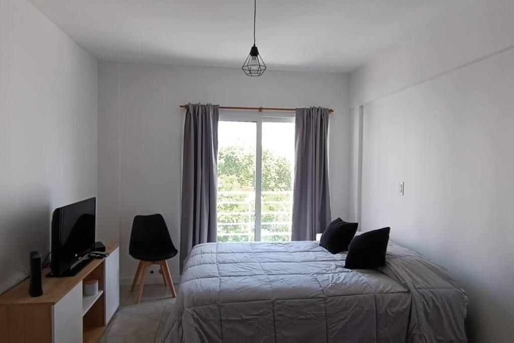 een slaapkamer met een bed en een groot raam bij Zit Flat in Mar del Plata