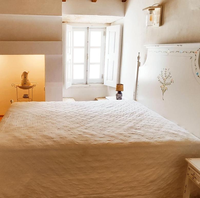 a large white bed in a room with a window at A Casa do Castelo in Estremoz