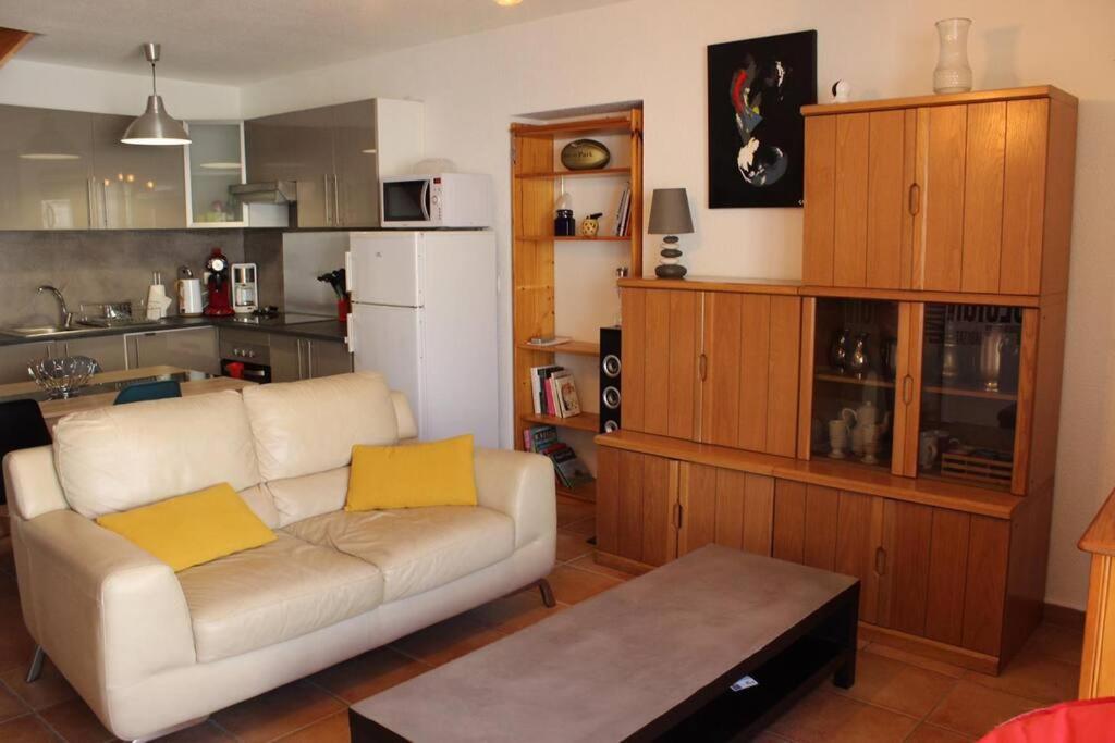sala de estar con sofá blanco y cocina en Agréable maison de village au calme en Sigean