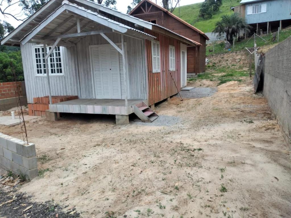 a small building with a porch on a dirt yard at Casa Temporada in Imbituba