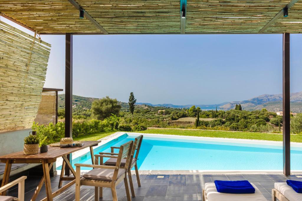 een patio met een tafel en stoelen en een zwembad bij FRG Villas - Villa Volare in Kefallonia