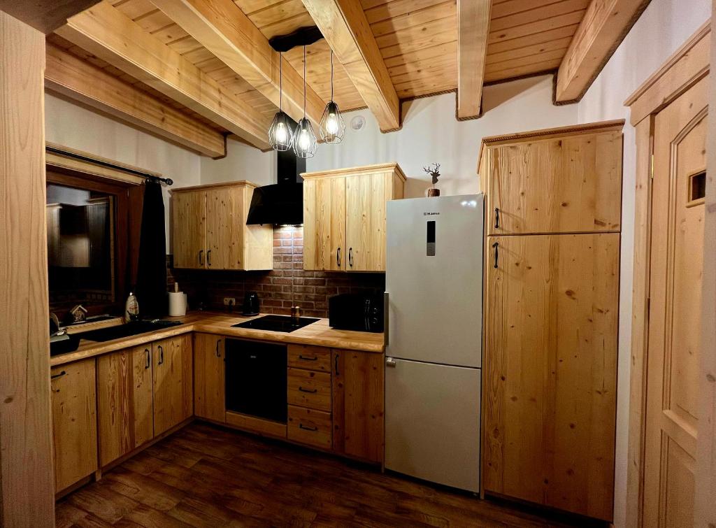 a kitchen with a white refrigerator and wooden cabinets at Domek Między Górami in Łapsze Niżne