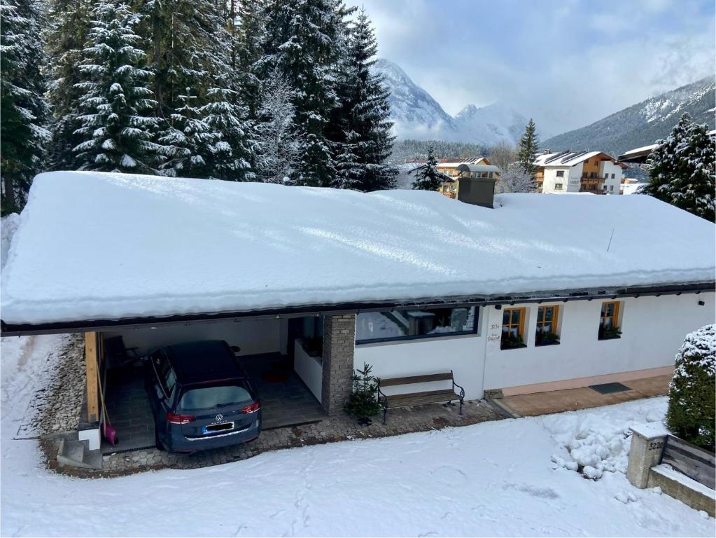 une voiture garée dans un garage avec de la neige sur le toit dans l'établissement Haus Drescher, à Leutasch