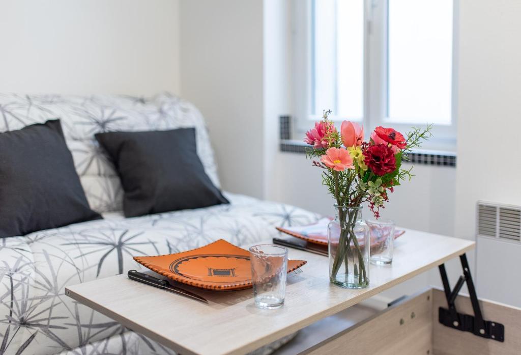 une table avec un vase de fleurs et un canapé dans l'établissement Le Champs Elysées - à 2 pas de la gare, à Toulouse