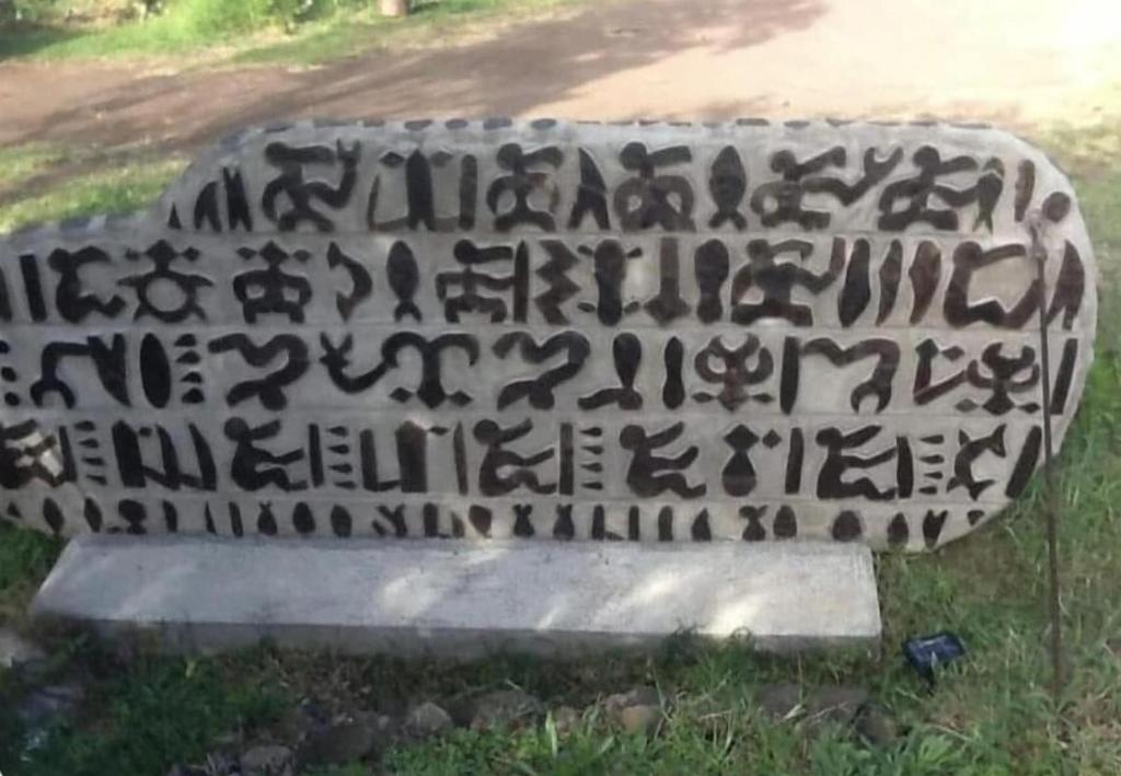 a stone sign with writing on it in the grass at Atavai Hotel Rapa Nui in Hanga Roa