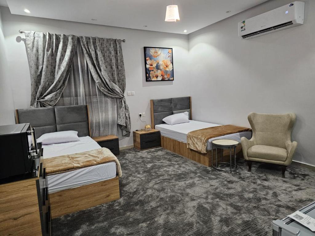 a hotel room with two beds and a chair at غرفة شذا طيبة المخدومة Shaza Taibah Luxury Room in Al Madinah