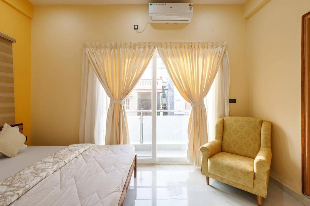 a bedroom with a bed and a chair and a window at 2 Bedroom Apartment near Vijayanagar, Bangalore in Bengaluru