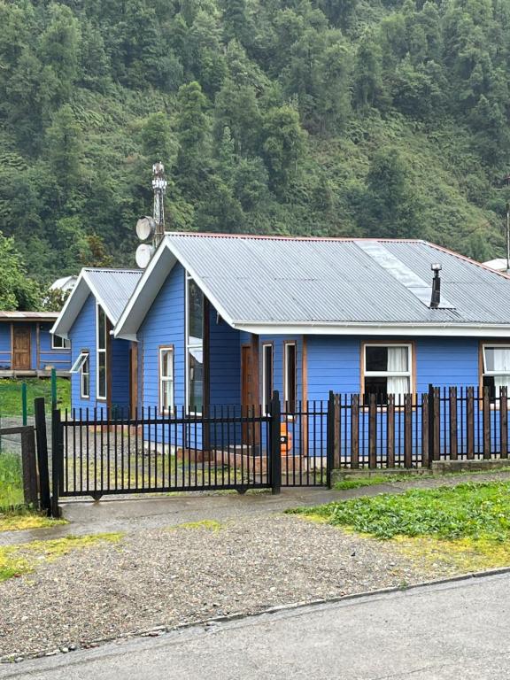una casa azul con una valla delante de ella en Cabañas kawi, en Puerto Cisnes
