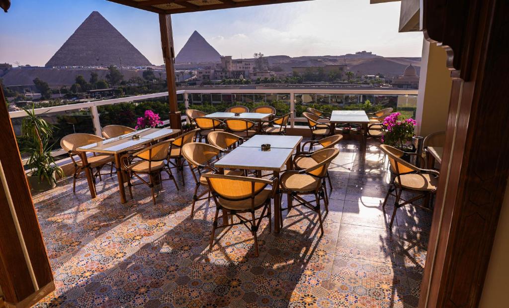 a patio with tables and chairs and the pyramids at DouDou Pyramids View Hotel in Cairo