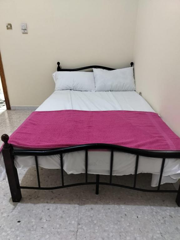 a bed with a pink blanket on top of it at Hussaini Home in Abu Dhabi