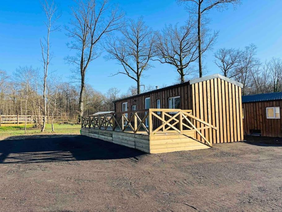 a wooden cabin with a gate and a fence at Equi-lodge vert au coeur des chevaux & de la nature proche Disney avec possibilité de balade poneys in La Houssaye-en-Brie