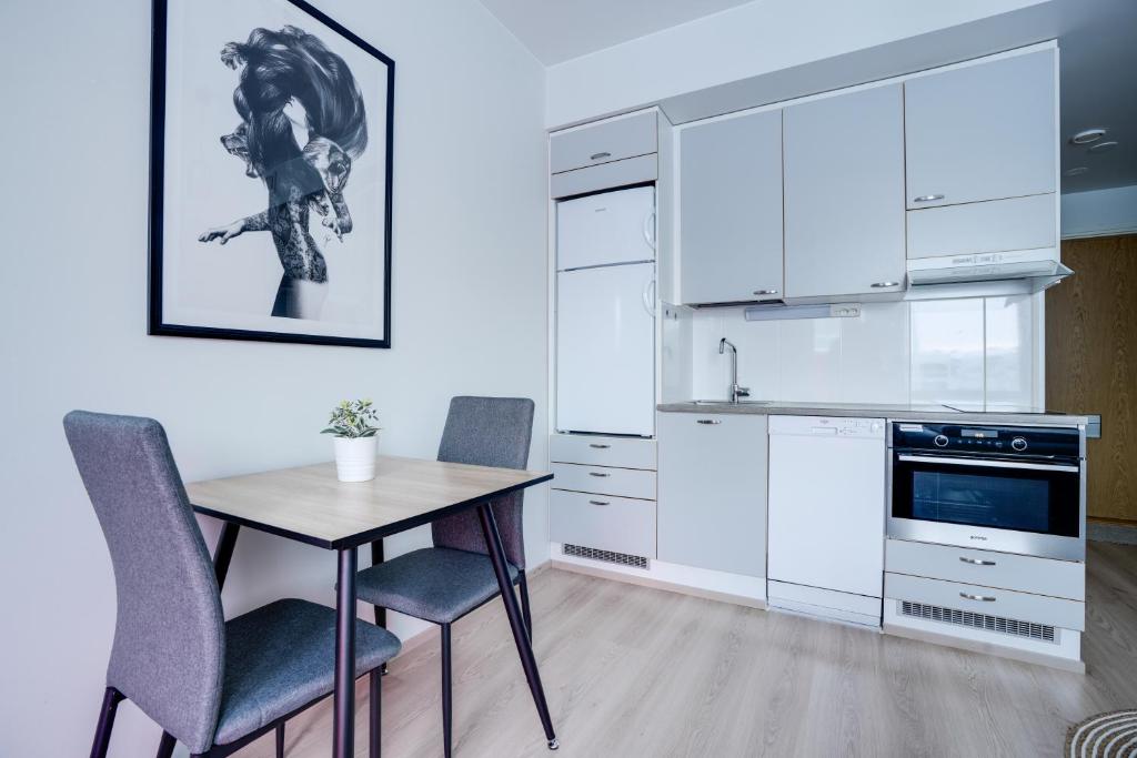 a kitchen with white cabinets and a table and chairs at Lapin Loiste 1, Modern studio, Free Parking and Wifi in Rovaniemi