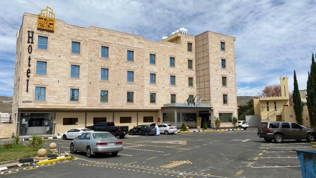 duży budynek z samochodami zaparkowanymi na parkingu w obiekcie Beautat Hotel w mieście Abha