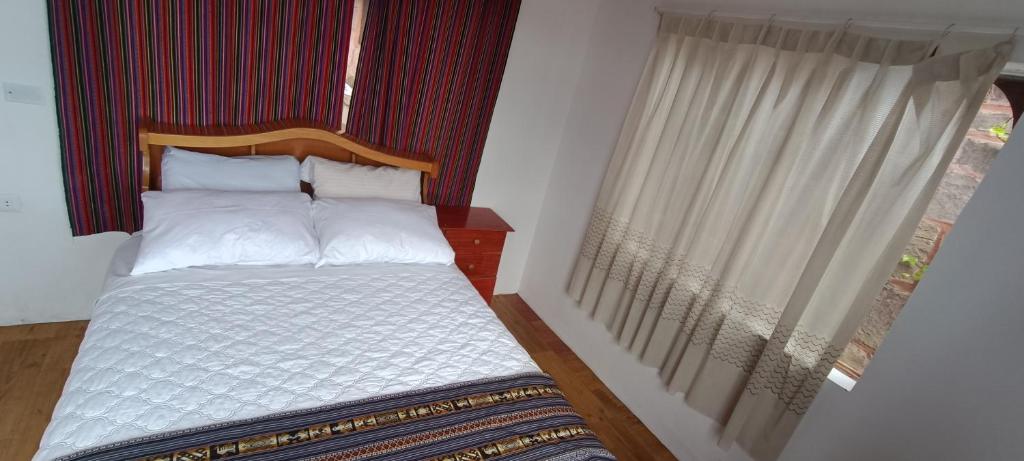 a small bedroom with a bed with a window at Taquile Lodge Inn in Huillanopampa