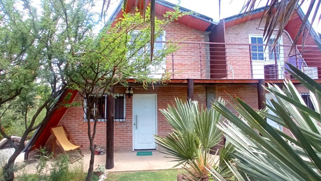 una casa de ladrillo rojo con puerta blanca en Cabañas Caranday en Capilla del Monte