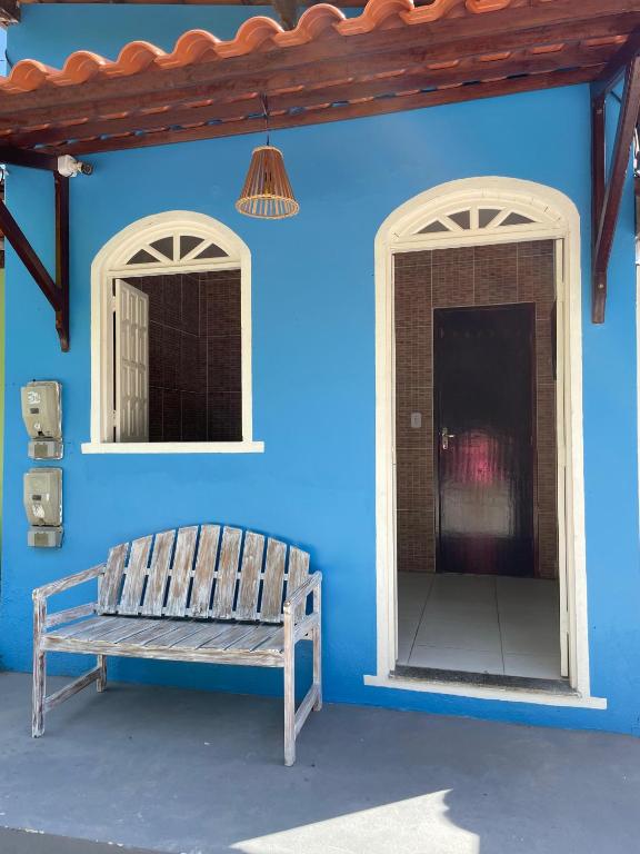 a blue wall with a bench and two windows at Small house in Ilha de Boipeba