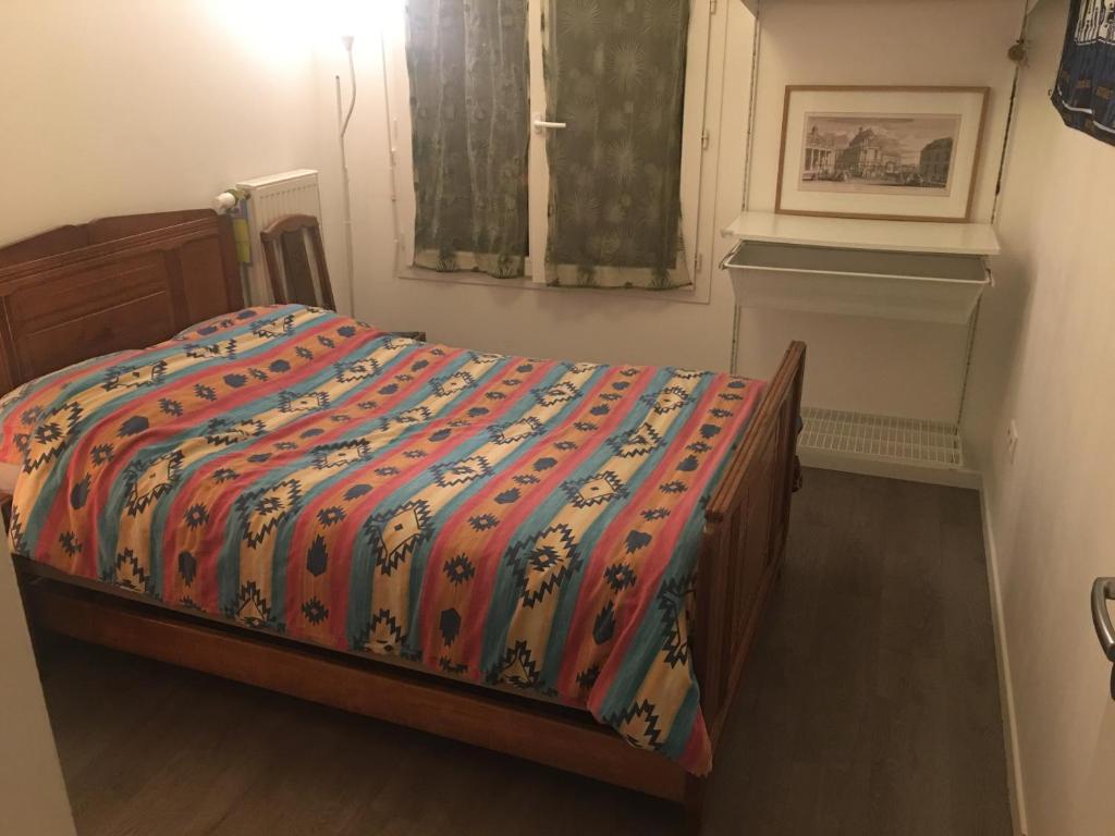 Una cama con un edredón colorido en un dormitorio en Chambres, en Trappes