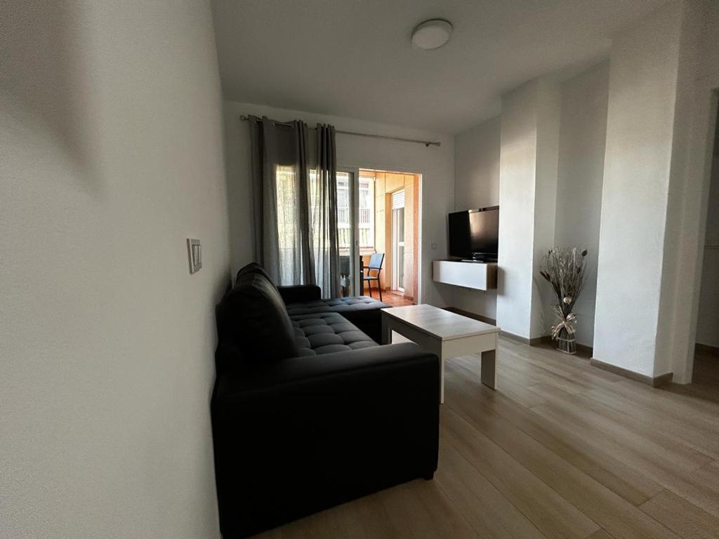 un salon avec un canapé noir et une table dans l'établissement Apartamento Elena, à Fuengirola