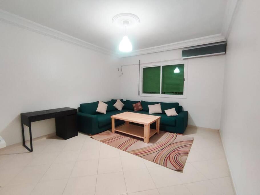 a living room with a green couch and a table at SkyRise Khemisset 2 : 2 bedrooms in Khemisset