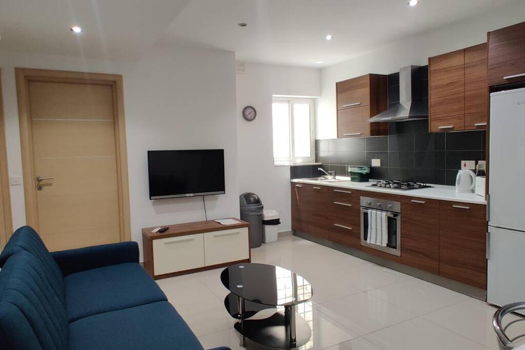 uma sala de estar com um sofá azul e uma cozinha em Apt B : Fun flat for up to 5+ Inc terrace em Is-Swieqi