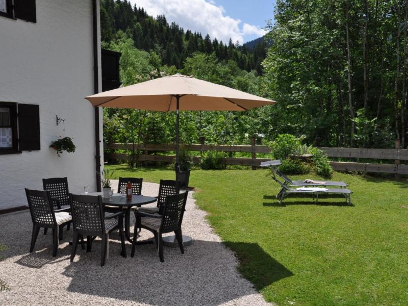 stół i krzesła z parasolem na dziedzińcu w obiekcie Forsthaus Reit im Winkl w mieście Reit im Winkl