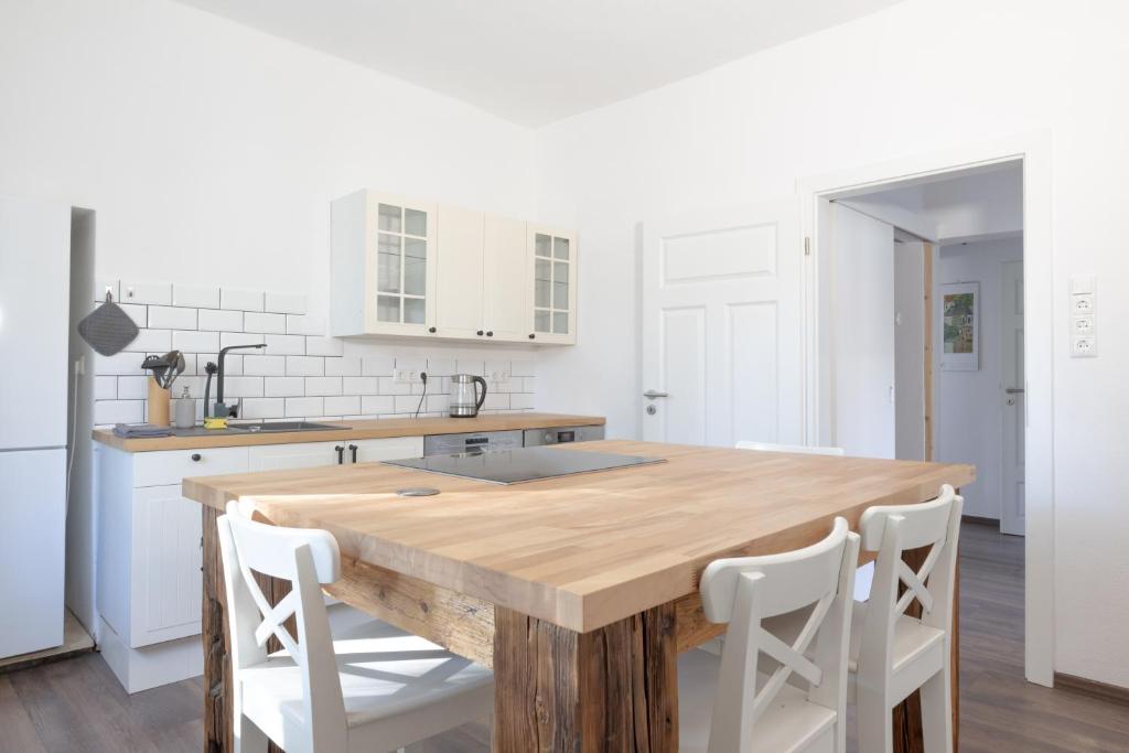 a kitchen with a wooden table and white cabinets at Urige Wohnung mit zwei Betten und genialer Küche in Mügeln