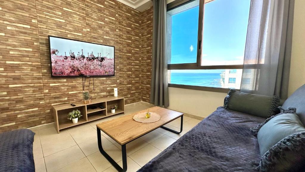- un salon avec un canapé et une télévision sur un mur en briques dans l'établissement Apartment with sea view, à Haïfa
