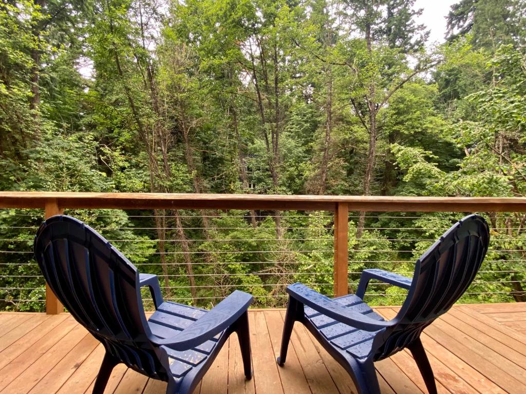 dos sillas azules sentadas en una terraza con árboles en Creekside Cottage in the City, en Portland