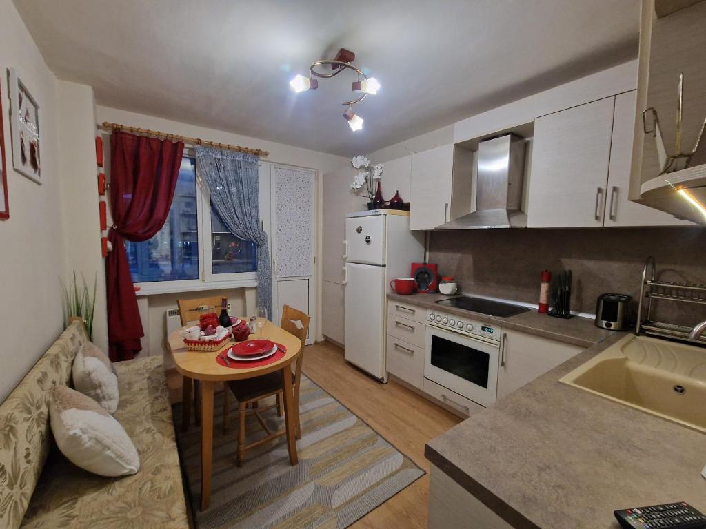 een keuken met een kleine tafel en een keuken met witte apparatuur bij Уютен 2-стаен Апартамент в Центъра на Добрич in Dobrich