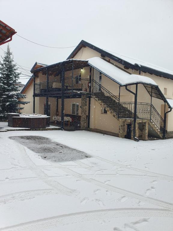 a house with snow on the ground in front of it at CASA LAURENTIU in Borşa