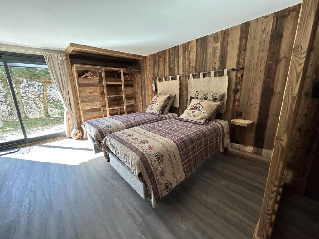 two beds in a room with wooden walls at Escargot de Neige in La Bresse