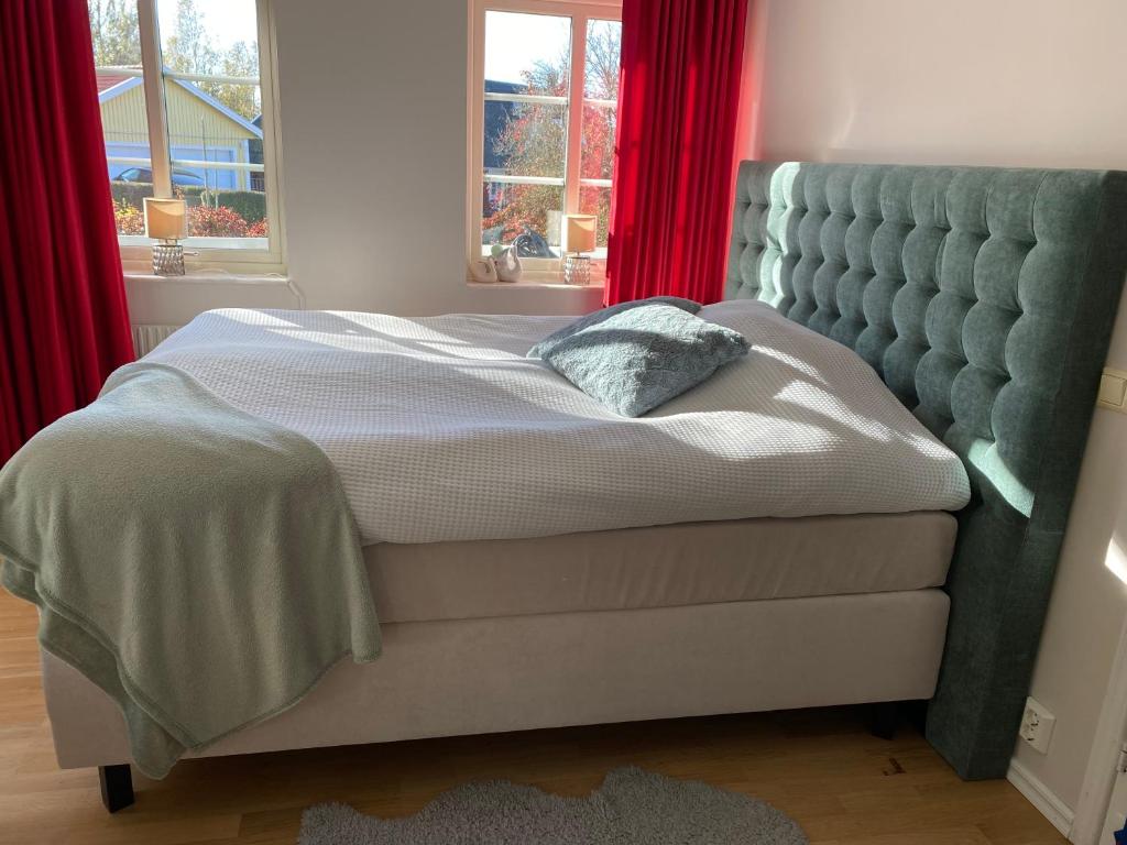 a bed in a bedroom with a red curtain at Family and Business Bed and Breakfast with a Beautiful Garden in Kallfors, Stockholm near a Golf Course, Lakes, the Baltic Sea, Forests & Nature in Järna
