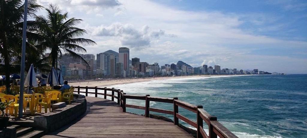 un paseo marítimo que conduce a una playa con ciudad en Lançamento,Duas suítes Leblon,segunda quadra da praia, en Río de Janeiro