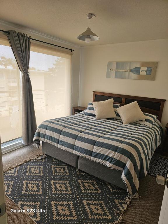 a bedroom with a blue and white bed with a window at Depto Parque Mar El Tabo in El Tabo