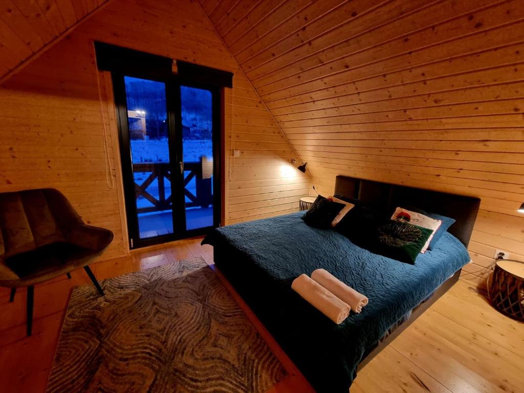 a bedroom with a bed in a wooden room with a window at Domek pod Ostoją Góry Sowie in Łomnica