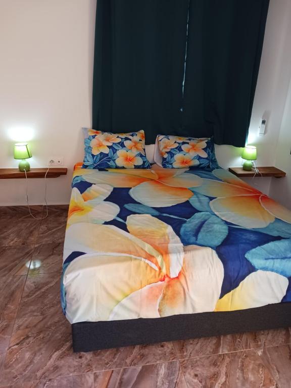 a bedroom with a bed with a colorful comforter and pillows at Ohana RBNB studio "Havai " in Uturoa