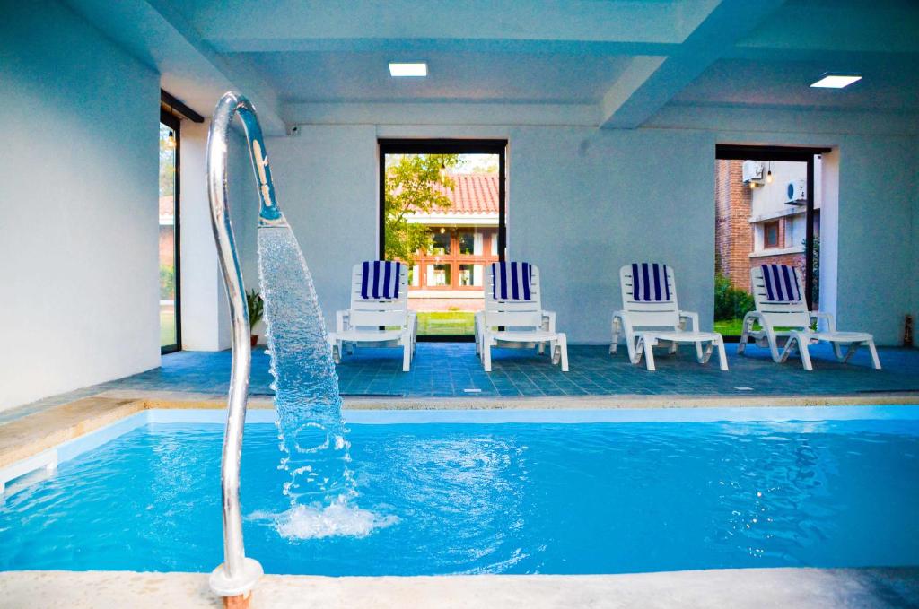 una piscina profunda con sillas y una fuente de agua en Hosteria Del Pescador, en Punta del Diablo